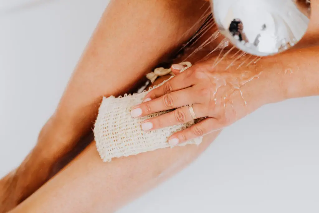 Close-up of woman washing her legs with a shower head. 