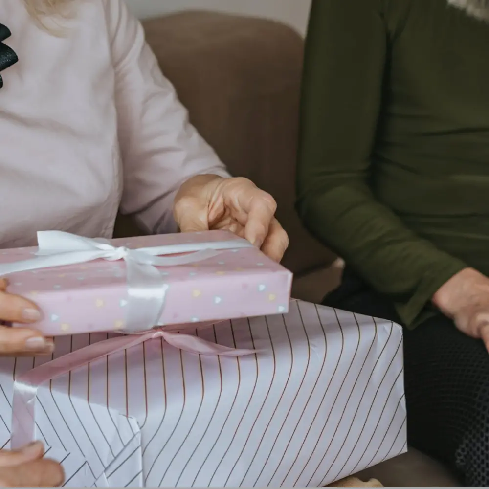 close up of woman holding gift next to another woman